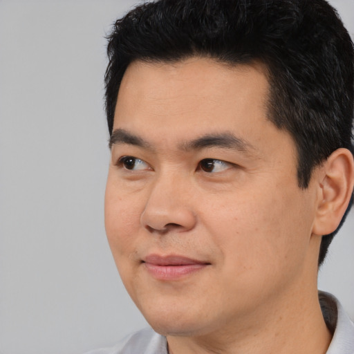 Joyful asian adult male with short  black hair and brown eyes