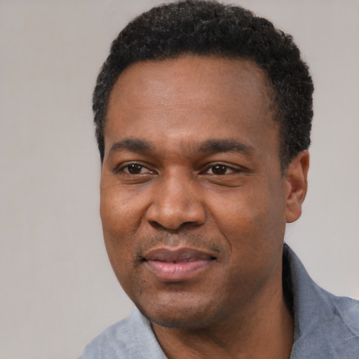 Joyful black adult male with short  black hair and brown eyes