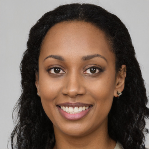 Joyful black young-adult female with long  black hair and brown eyes