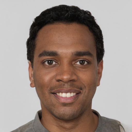 Joyful black young-adult male with short  black hair and brown eyes