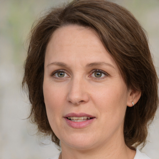 Joyful white adult female with medium  brown hair and green eyes