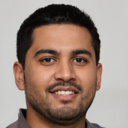 Joyful latino young-adult male with short  black hair and brown eyes