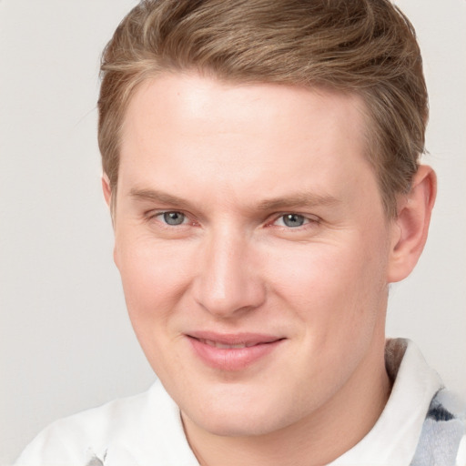 Joyful white young-adult male with short  brown hair and blue eyes