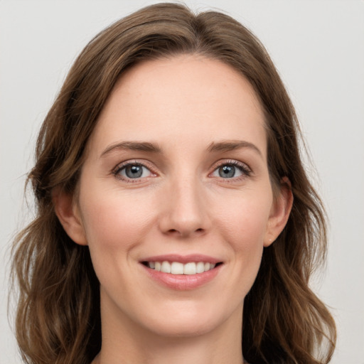 Joyful white young-adult female with long  brown hair and blue eyes