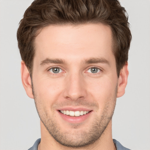 Joyful white young-adult male with short  brown hair and grey eyes