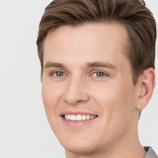 Joyful white young-adult male with short  brown hair and grey eyes