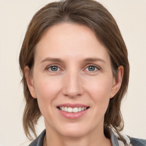 Joyful white young-adult female with medium  brown hair and grey eyes