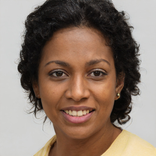 Joyful black young-adult female with long  brown hair and brown eyes