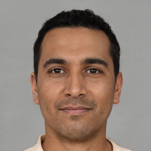 Joyful latino young-adult male with short  black hair and brown eyes
