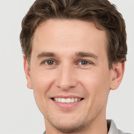 Joyful white young-adult male with short  brown hair and grey eyes