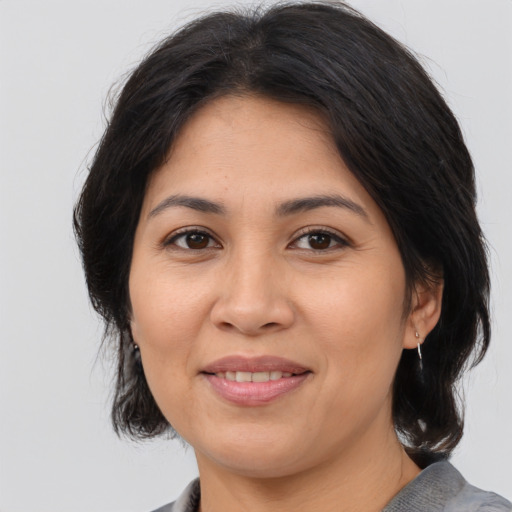 Joyful latino adult female with medium  brown hair and brown eyes