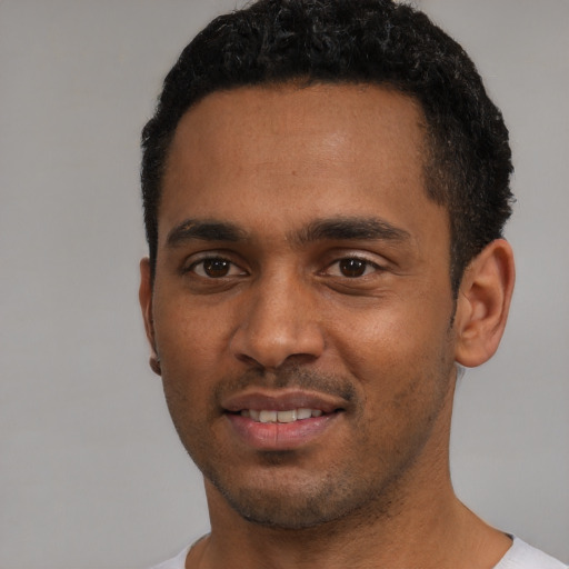 Joyful black young-adult male with short  black hair and brown eyes