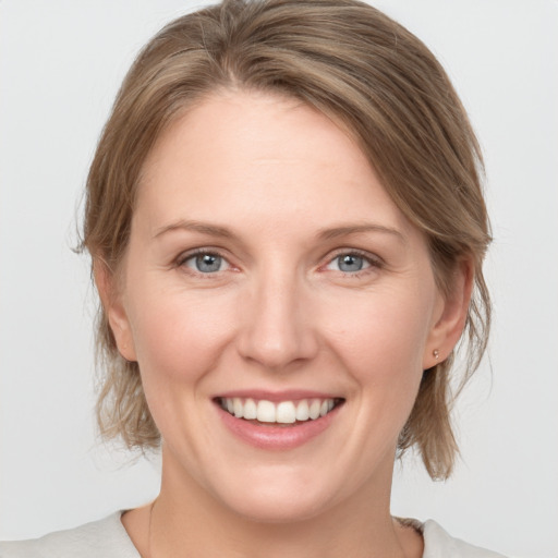 Joyful white young-adult female with medium  brown hair and grey eyes