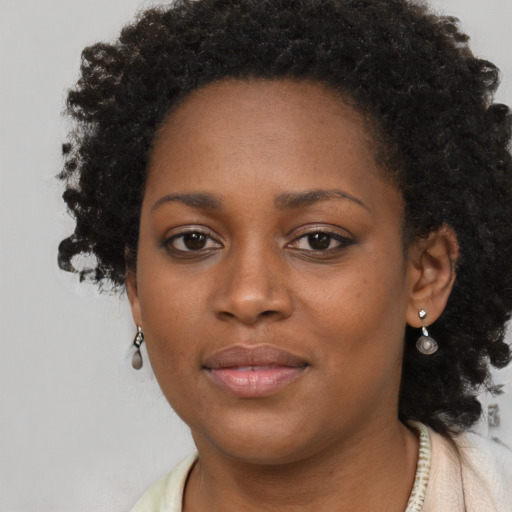 Joyful black young-adult female with long  brown hair and brown eyes