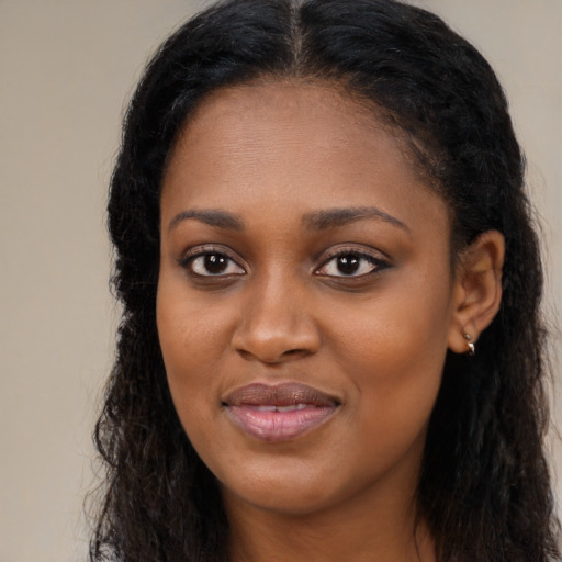 Joyful black young-adult female with long  black hair and brown eyes