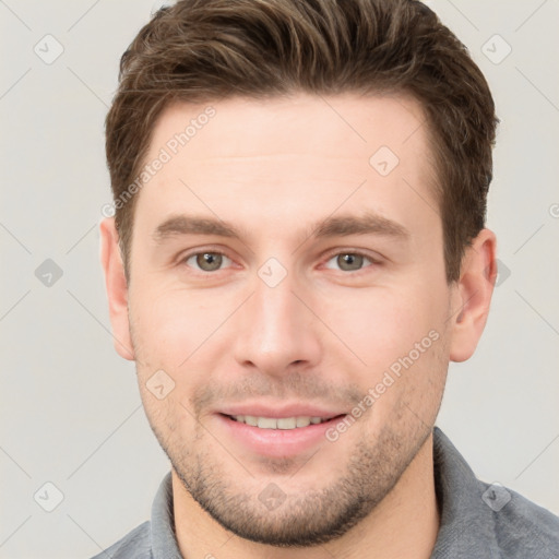 Joyful white young-adult male with short  brown hair and grey eyes