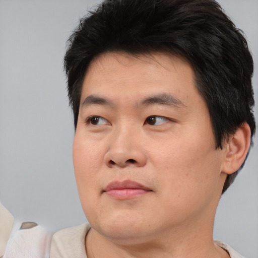 Joyful asian young-adult male with short  brown hair and brown eyes