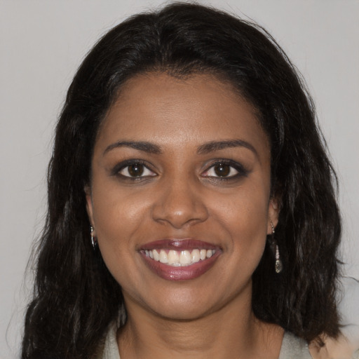 Joyful black young-adult female with long  brown hair and brown eyes