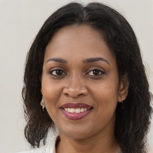 Joyful black young-adult female with long  brown hair and brown eyes