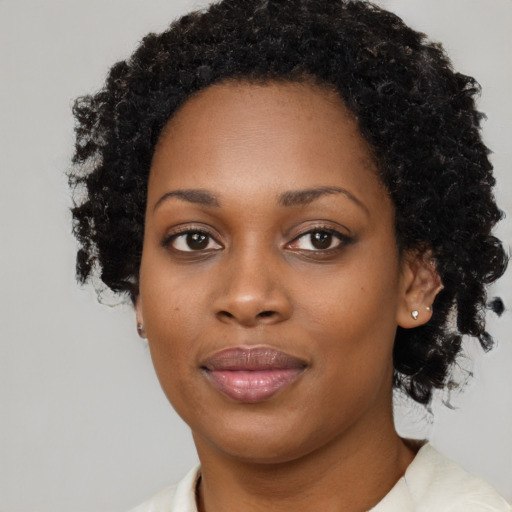 Joyful black young-adult female with short  black hair and brown eyes