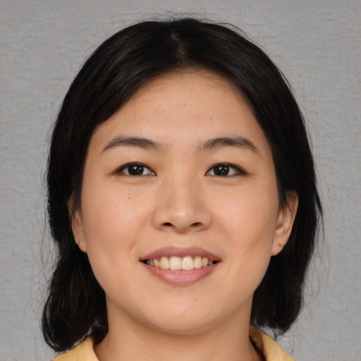 Joyful asian young-adult female with medium  black hair and brown eyes