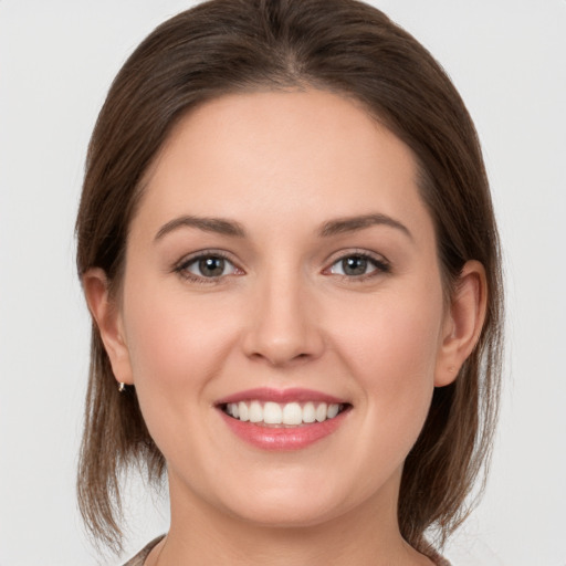 Joyful white young-adult female with medium  brown hair and grey eyes