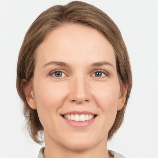 Joyful white young-adult female with medium  brown hair and grey eyes