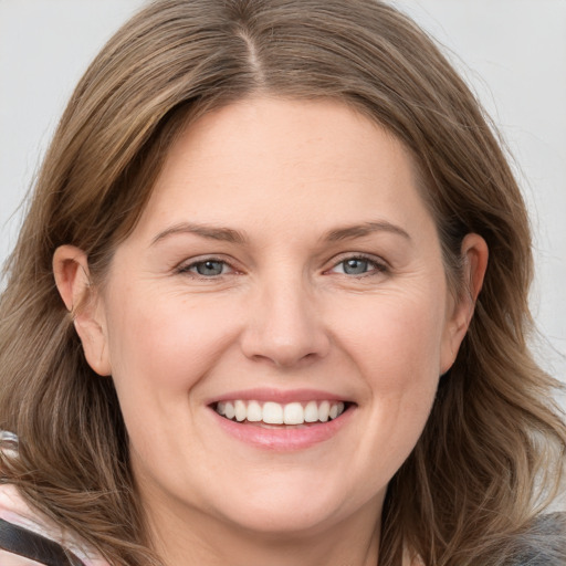 Joyful white young-adult female with long  brown hair and grey eyes