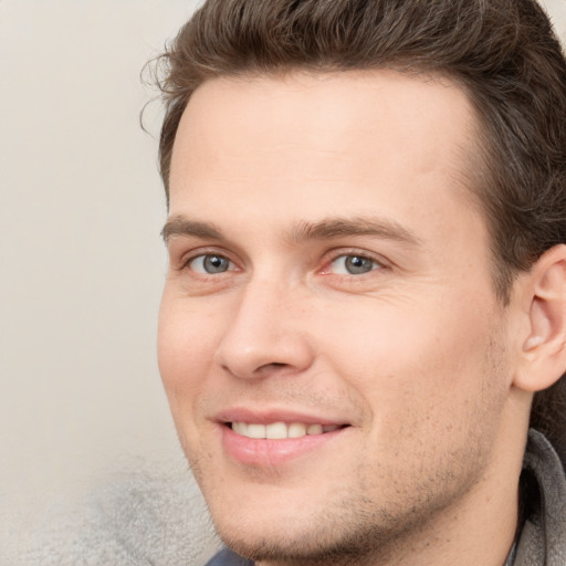 Joyful white young-adult male with short  brown hair and grey eyes