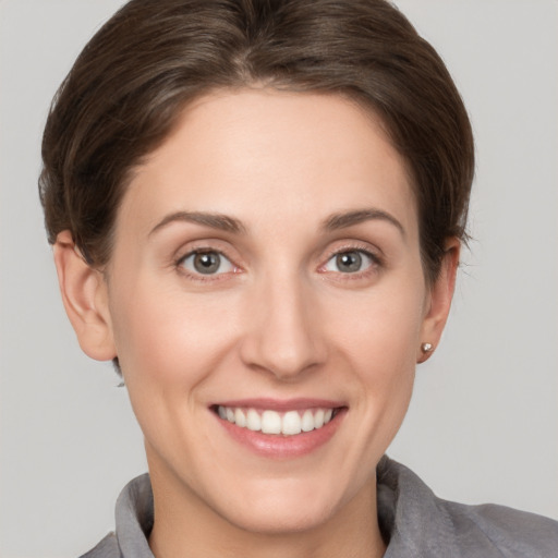 Joyful white young-adult female with short  brown hair and grey eyes