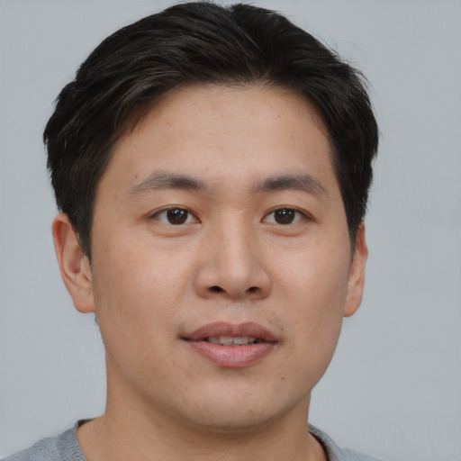 Joyful asian young-adult male with short  brown hair and brown eyes