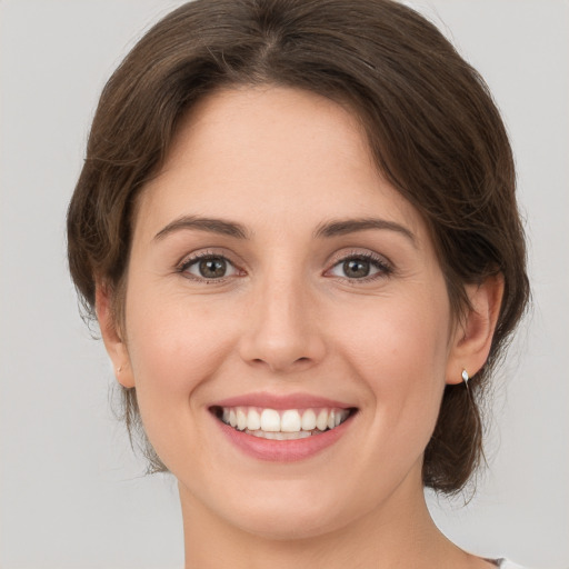 Joyful white young-adult female with medium  brown hair and grey eyes