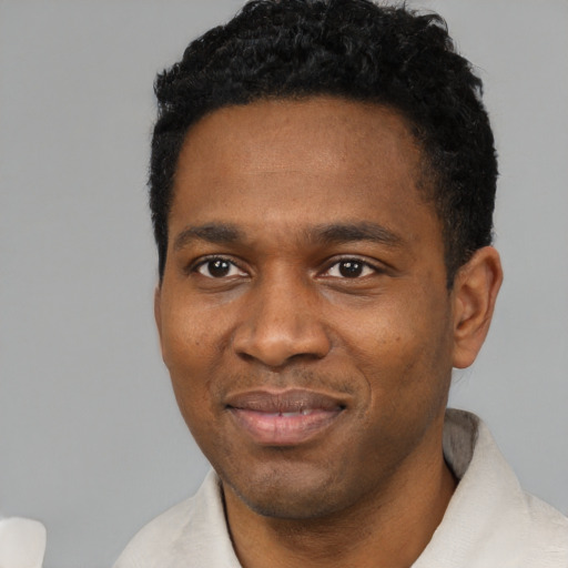 Joyful black young-adult male with short  black hair and brown eyes