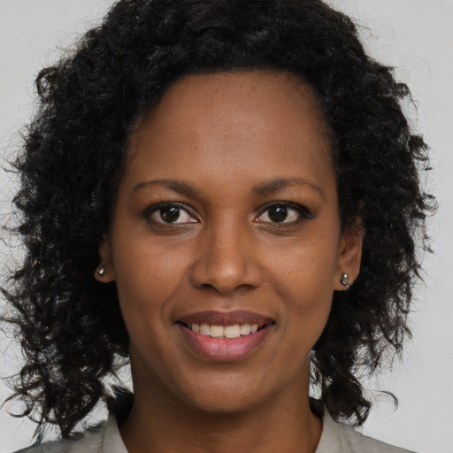 Joyful black young-adult female with long  brown hair and brown eyes
