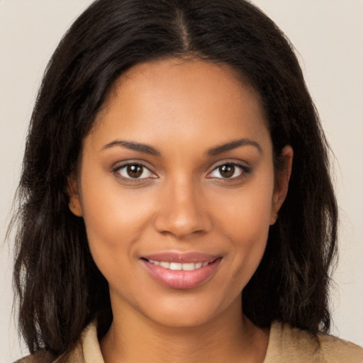 Joyful black young-adult female with long  brown hair and brown eyes