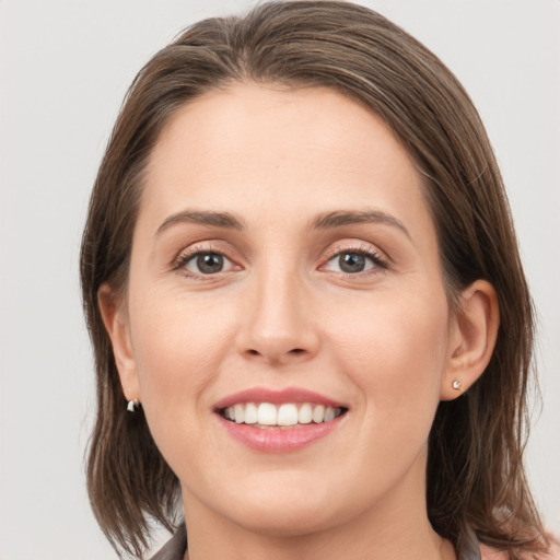 Joyful white young-adult female with medium  brown hair and grey eyes