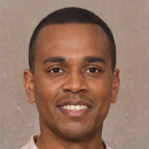 Joyful black young-adult male with short  brown hair and brown eyes