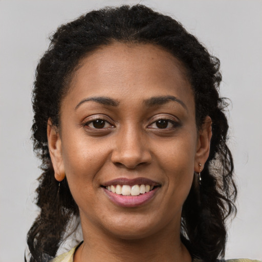 Joyful black young-adult female with long  brown hair and brown eyes
