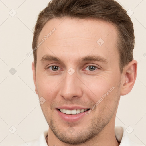 Joyful white young-adult male with short  brown hair and grey eyes