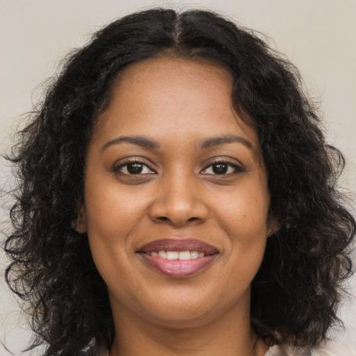 Joyful black young-adult female with long  brown hair and brown eyes