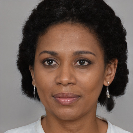 Joyful black young-adult female with short  black hair and brown eyes