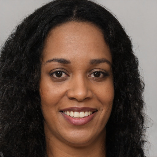 Joyful black young-adult female with long  brown hair and brown eyes