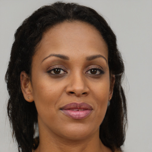 Joyful black adult female with long  brown hair and brown eyes
