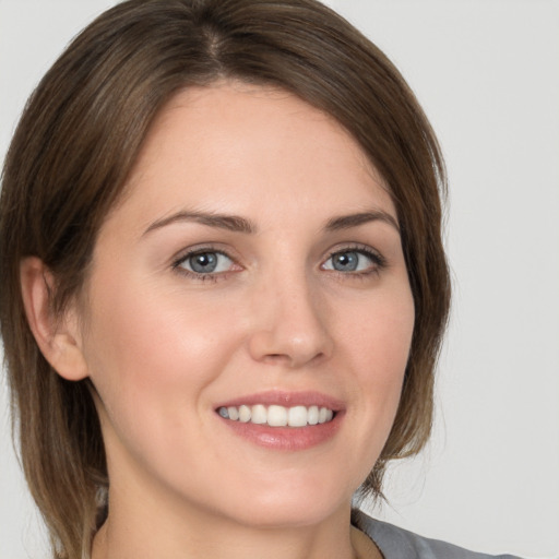 Joyful white young-adult female with medium  brown hair and grey eyes