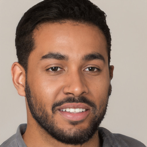 Joyful black young-adult male with short  black hair and brown eyes