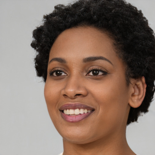 Joyful black young-adult female with short  black hair and brown eyes