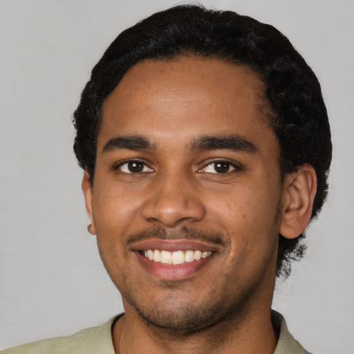 Joyful black young-adult male with short  black hair and brown eyes