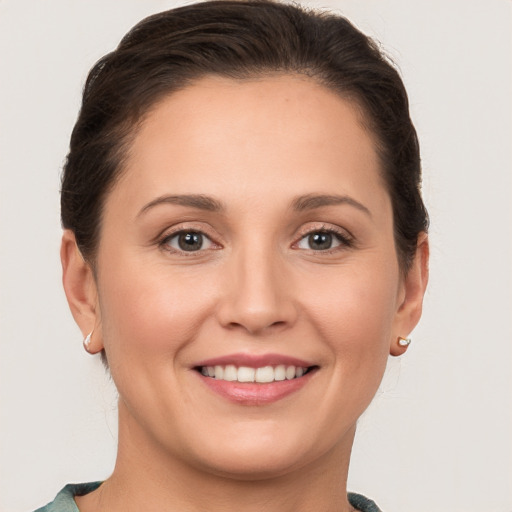 Joyful white young-adult female with medium  brown hair and grey eyes