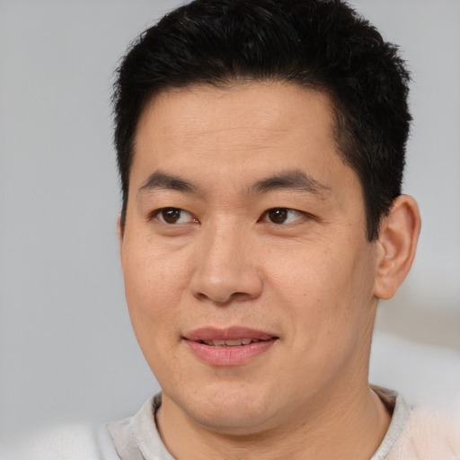 Joyful asian young-adult male with short  brown hair and brown eyes