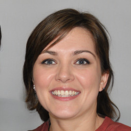 Joyful white young-adult female with medium  brown hair and blue eyes